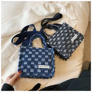 Detail of checkered denim tote bags in blue and grey with frayed edges and wide straps