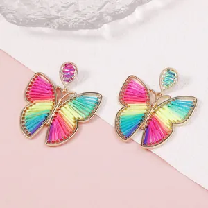 Detalle de pendientes de mariposa tejidos a mano con marco de aleación dorada e hilos de colores