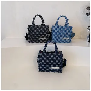 Detail of plaid denim tote bags featuring frayed edge texture in blue and grey colors