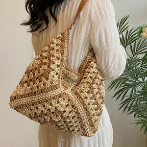 Women's woven straw beach tote bag with brown leather strap and contrast patterns