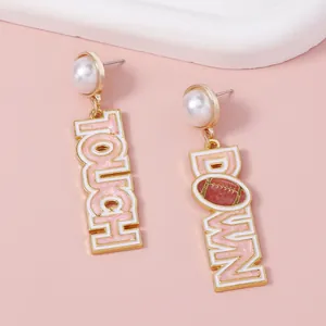 Detailed close-up of pearl studs and pink enamel football touchdown drop earrings