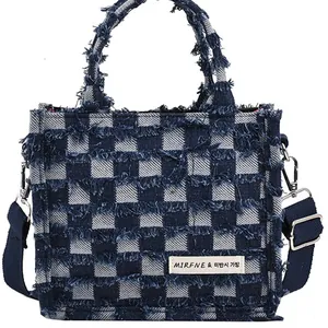 Frayed denim checkerboard tote bag with adjustable shoulder strap and tassel details