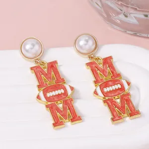 Vue macro des boucles d'oreilles MOM dorées avec émail rouge et détail rugby