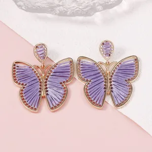 Detalle de los pendientes de mariposa hechos a mano con seda morada y marco dorado