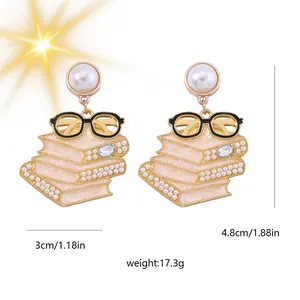 Detailansicht der Ohrringe im Buchstapel-Design mit Kunstperlen und goldener Brille