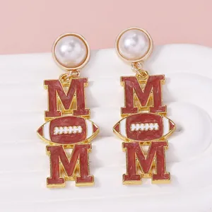 Vue détaillée de boucles d'oreilles dorées avec lettres MOM et motif rugby perle