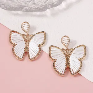 Detalle de pendientes de mariposa hechos a mano con elegantes marcos de aleación dorada
