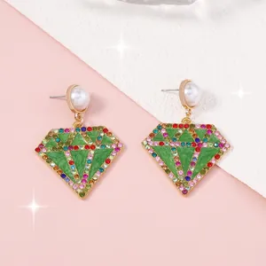 Detalle de pendientes geométricos con incrustación verde y cristales de varios colores