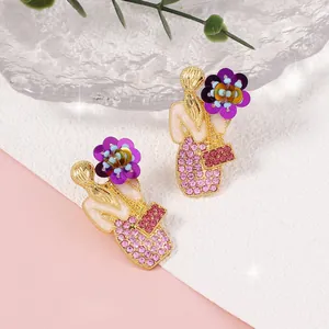 Dettaglio orecchini fatti a mano a forma di donna con fiori di paillettes viola e cristalli