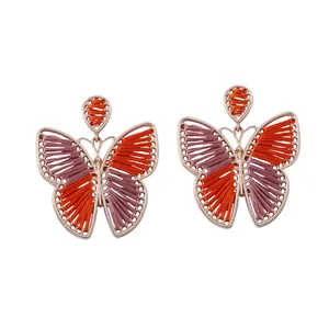 Detalle de pendientes de mariposa hechos a mano con hilos de seda de colores vivos