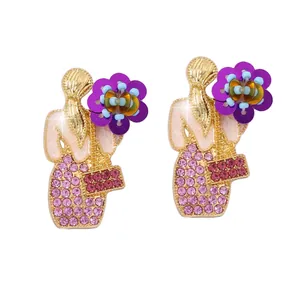 Dettaglio dell'orecchino a ritratto fatto a mano con strass rosa e fiori viola