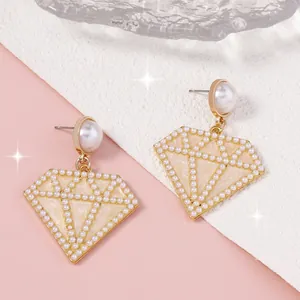 Detalle de pendientes geométricos en forma de diamante con perlas artificiales y oro