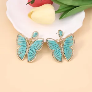 Detalle de pendientes de mariposa tejidos a mano en azul con borde de aleación oro