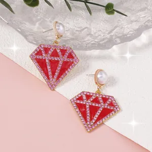 Detalle de pendientes de rombo en esmalte rojo con brillantes rosas y perlas finas