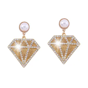 Detalle de pendientes geométricos con perlas de imitación blancas y cristales brillantes