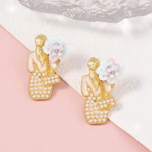 Dettaglio di orecchini floreali fatti a mano con perle e design dorato elegante