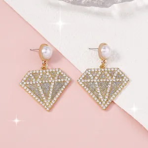 Detalle de pendientes geométricos con forma de diamante, perla sintética y cristales