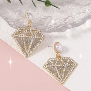 Detalle de pendientes colgantes en forma de diamante con pedrería blanca y una perla