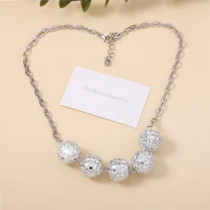 Silver necklace with five glittering disco ball pendants on a minimalist white display card
