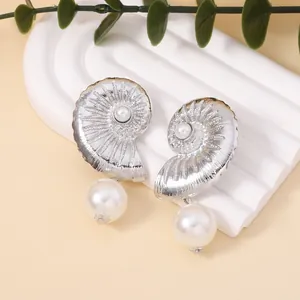 Silver conch shell earrings with white pearl drop on elegant neutral background