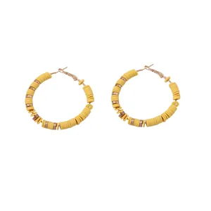 Detailopname van bohemian gele heishi kraal oorringen met gouden metalen afstandhouders