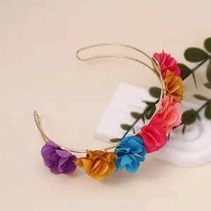 Detail of a gold double-row headband with colorful fabric flowers on a display stand