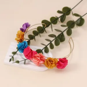 Detailed macro of colorful fabric flowers on a slim golden U-shaped metal headband