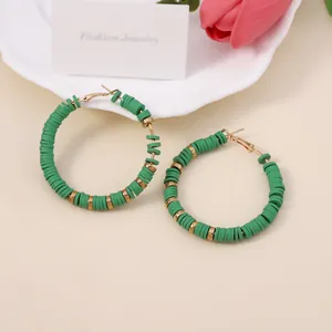 Detail van bohemien ronde groene polymeerklei oorringen met gouden metalen kralen