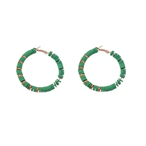 Detail van groene polymeerklei kralen oorringen met gouden metalen accenten