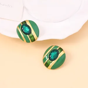 Detalle macro de pendientes ovalados de esmalte verde con centro de esmeralda