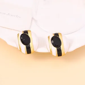 Detalle de pendientes retro con esmalte de rayas blancas y negras y gema facetada