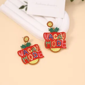 Macro detail of handmade beaded earrings with VACAY MODE text in vibrant red and green