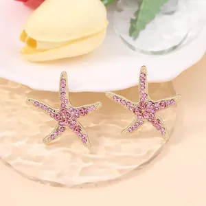 Macro detail of starfish earrings with pink zircon pavé on a golden base design