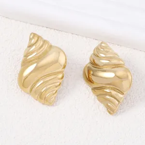 Vintage golden conch shell stud earrings with polished pearl finish on white sand
