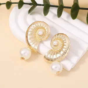 Detail of vintage gold shell earrings with radiant textures and large pearl drops