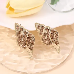 Macro view of gold seashell earrings with sparkling champagne zircon and beaded edges