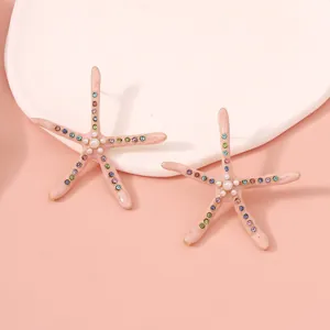 Close-up of pink starfish earrings with colorful zircons and central pearl detail