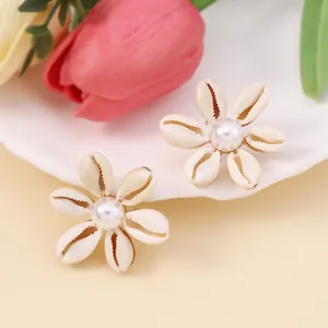 Detail of seashell flower stud earrings with white pearl center for beach style