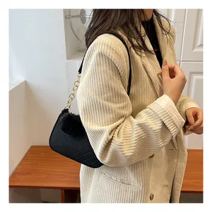 Close-up of black crossbody bag featuring V-shaped quilting and a fluffy fur ball charm