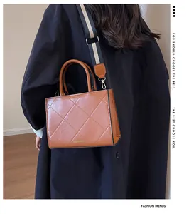 Detail of a brown quilted square handbag with fashionable striped wide shoulder strap