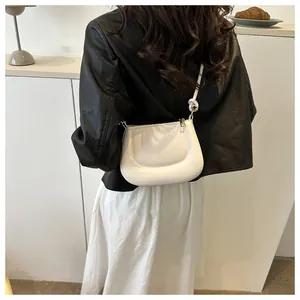 Elegante borsa a tracolla in pelle bianca con dettaglio tracolla annodata su modella