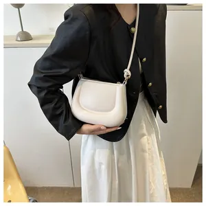 Elegante borsa a sella color crema abbinata a giacca in pelle nera e gonna bianca