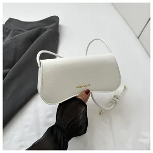 Detail of white crocodile texture underarm bag with gold fashion lettering and thin strap