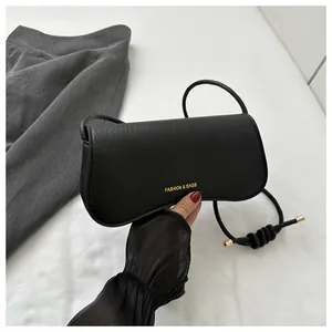 Detail showing crocodile texture leather, gold knots, and fashion logo on black bag