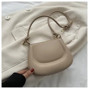 Dettaglio borsa a tracolla beige minimalista in pelle morbida con nodo sulla tracolla