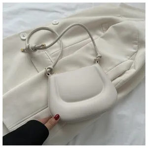 Dettaglio della borsa a mezzaluna bianco sporco con texture a pieghe e dettagli oro