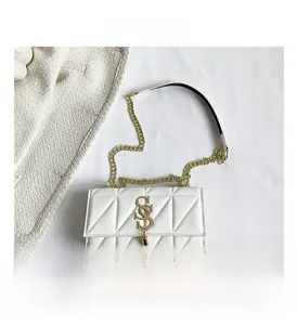 Close-up of white quilted faux leather bag with gold metal logo and chain strap details