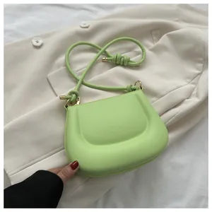Dettaglio borsa quadrata verde pistacchio con tracolla a nodi su blazer bianco
