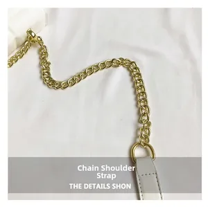 Detail view of glossy gold metal chain strap and fine stitching on a white shoulder bag