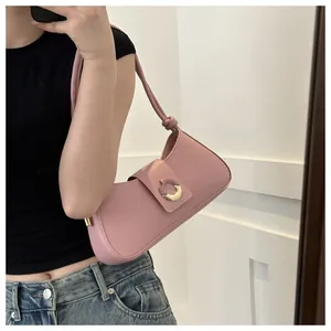Detailed close-up of a pink matte leather underarm bag with a gold metal buckle and knot